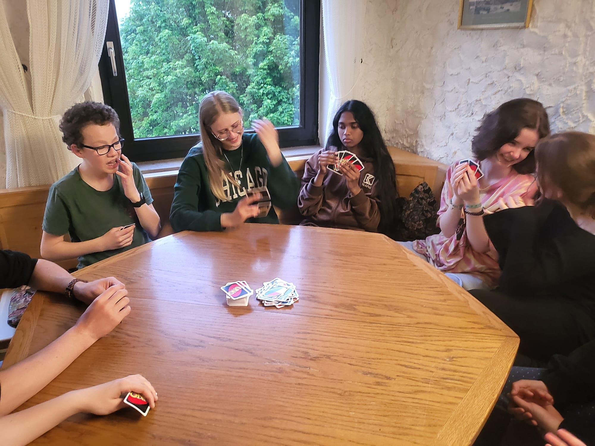 Gruppe spielt abends Karten am großen Tisch in der Wiesenhütte